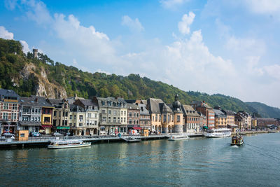 Sailboats in lake by buildings against sky