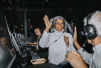 Happy senior couple giving high-five while winning video game at gaming center