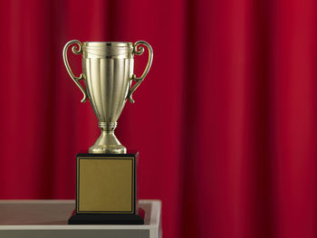 Close-up of trophy on table against red curtain