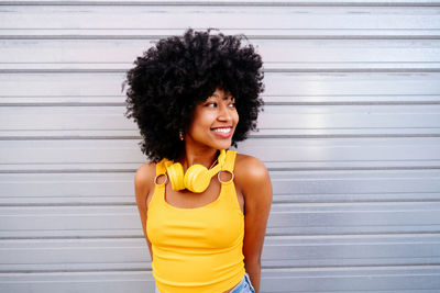 Portrait of young woman standing against wall