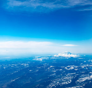 Aerial view of snowcapped mountain against blue sky