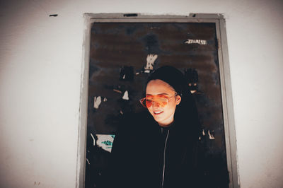 Portrait of a smiling young man standing against wall