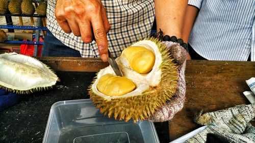 Midsection of man selling durian at market stall