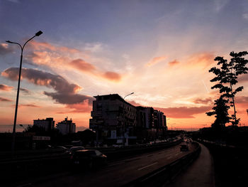 Cars on road against sky during sunset