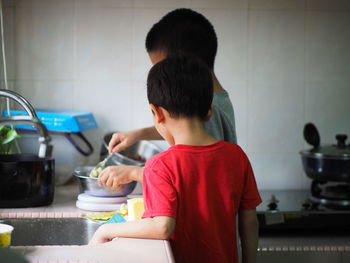 Siblings preparing food in kitchen