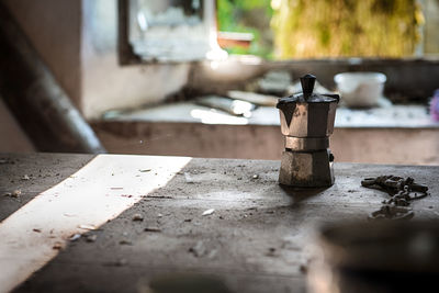 Close-up of kettle on wooden table in weathered kitchen