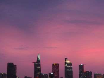 Illuminated buildings against pink sky during sunset