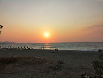 Silhouette people on beach against sky during sunset