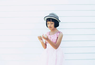 Full length of girl standing against wall