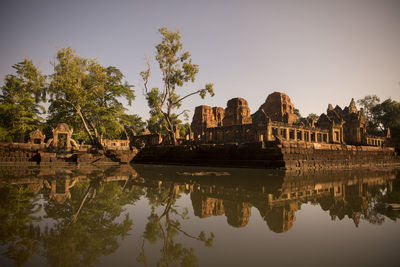 Prasat ta muen thom temple by lake against clear sky