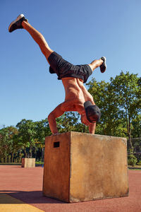 Low angle view of man jumping against clear sky