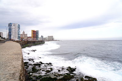 Scenic view of sea by buildings against sky