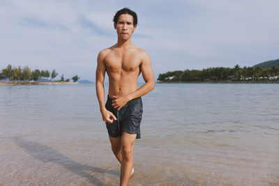 Shirtless man standing in lake