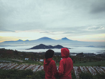 Rear view of people looking at mountain against sky