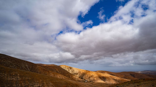Scenic view of mountain range against cloudy sky
