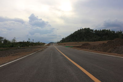 Empty road amidst trees against sky