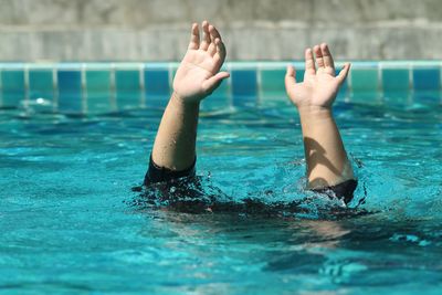 Cropped hands of boy standing in swimming pool