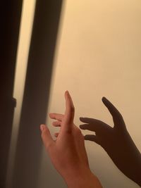 Cropped hand of woman pointing against wall in home