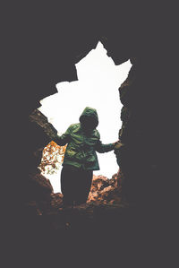 Low angle view of man standing on rock against sky