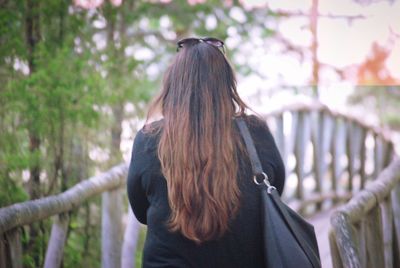 Rear view of woman standing against railing