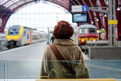 Rear view of woman standing at railroad station platform