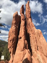 Low angle view of rocks on mountain against cloudy sky