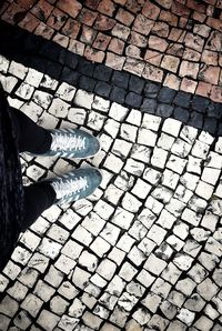 Low section of person standing on cobblestone street