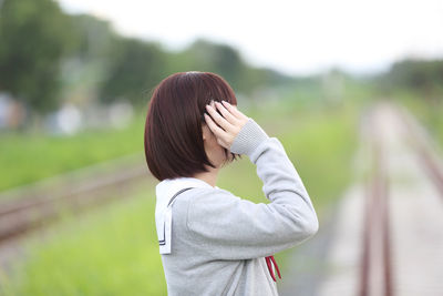 Young woman in school uniform standing on railroad tracks