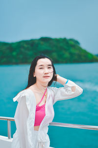 Portrait of young woman standing against sky