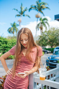 Portrait of young woman standing against trees