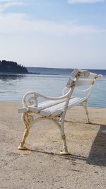 Deck chairs on beach against sky