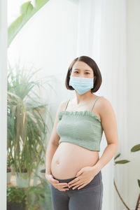 Pregnant woman standing by window at home