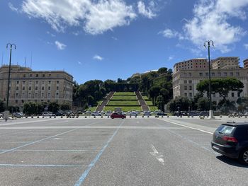 Road by buildings against sky in city