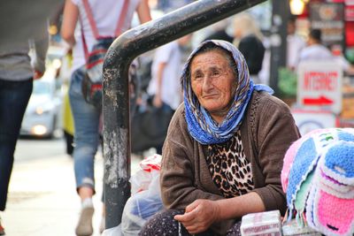 Senior woman looking away while sitting on street