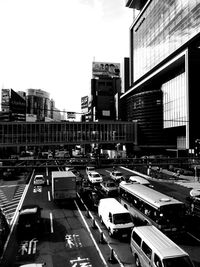 Traffic on road by buildings in city against sky