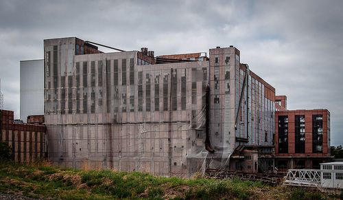 Abandoned factory by building against sky