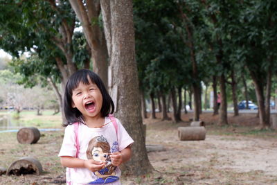 Cute girl laughing while standing against trees