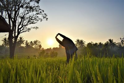 Man standing on field against sky during sunset