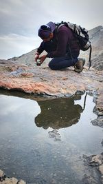 People on rock in lake against sky