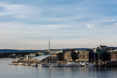 Sailboats in harbor by buildings against sky