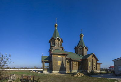 Church by building against clear blue sky