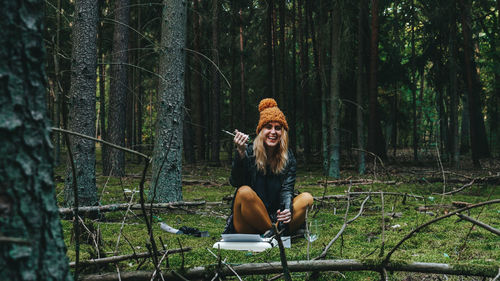 Girl laughing while opening wine bottle in forest