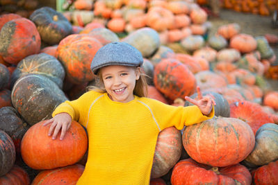 Portrait of cute girl standing against pumpkins