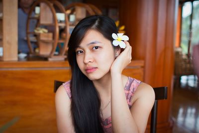 Portrait of young woman looking away while sitting at home