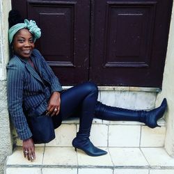 Portrait of smiling young woman sitting on door