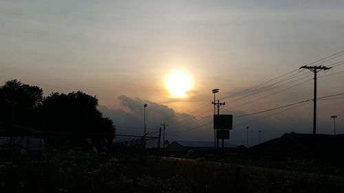 Silhouette electricity pylon against sky during sunset