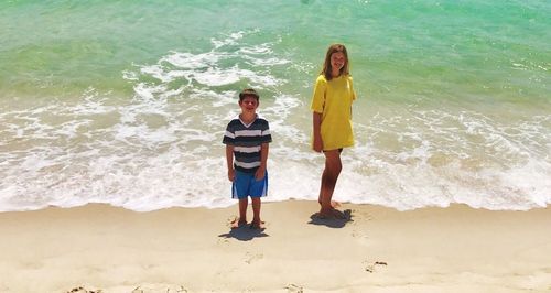 Full length portrait of happy friends standing on beach