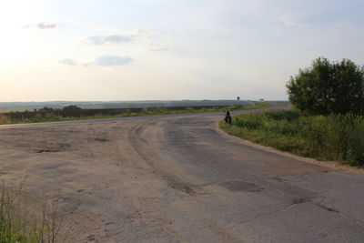 Road amidst field against sky