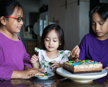 Cute siblings sitting by cake at home