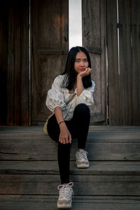 Portrait of young woman sitting on wood